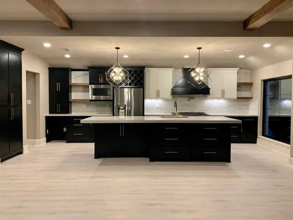 The kitchen boasts a striking design with black cabinets and white counter tops.