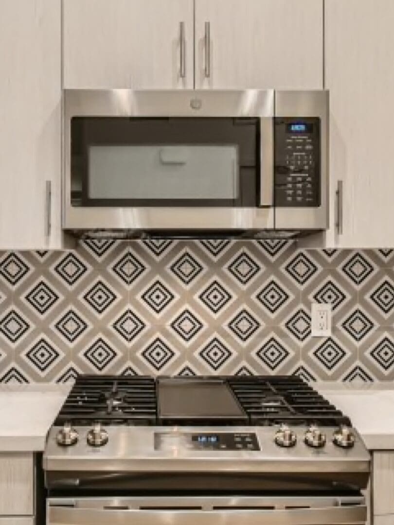A kitchen with a stainless steel stove and modern tile backsplash design.