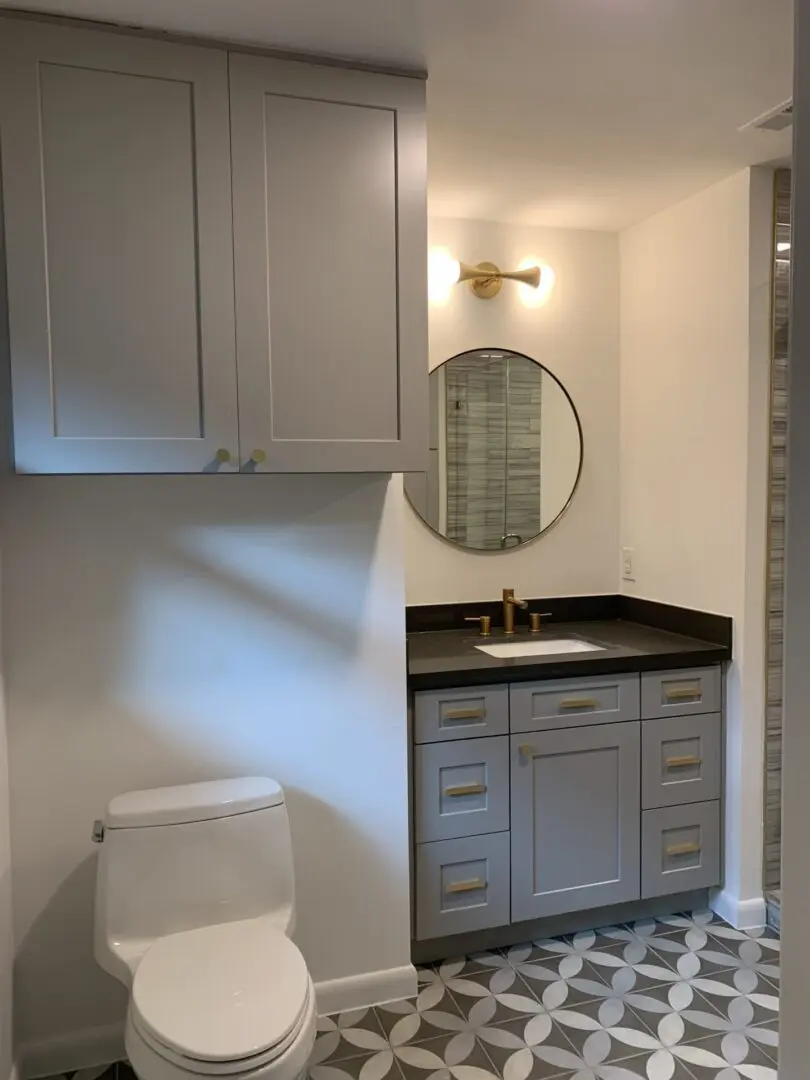 A bathroom with gray cabinets and a toilet.