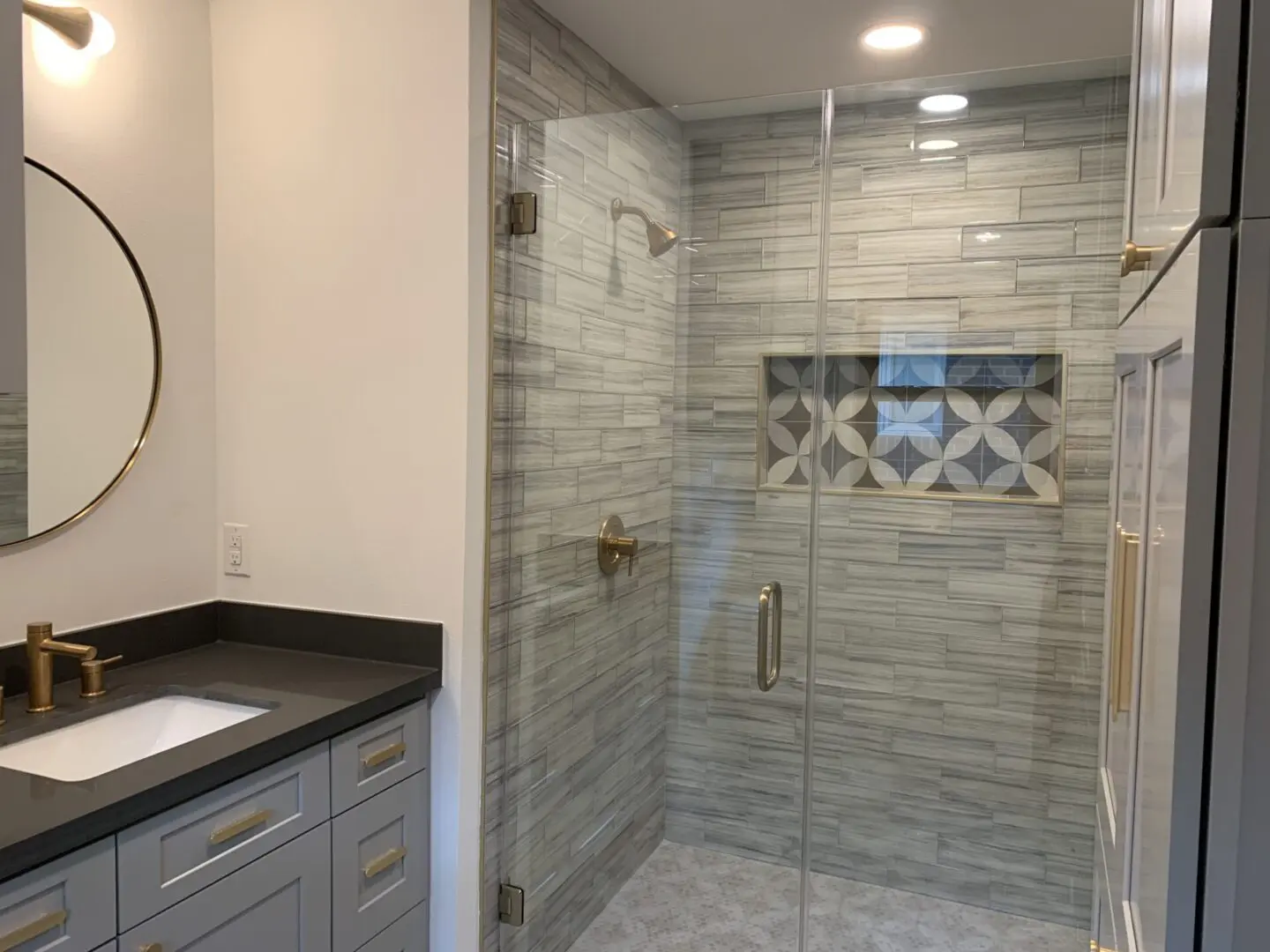 A bathroom with a glass shower stall and marble counter top.