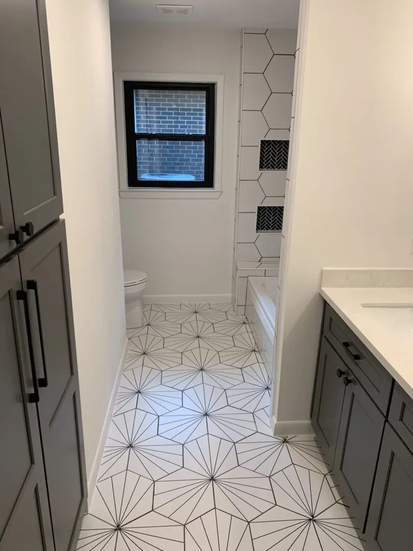 A bathroom with a gray tile floor and white cabinets.