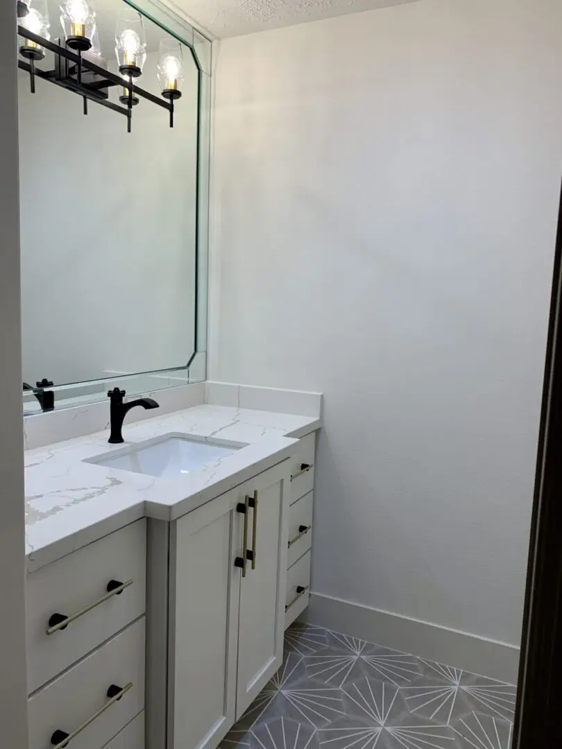 A bathroom with white cabinets and a mirror.