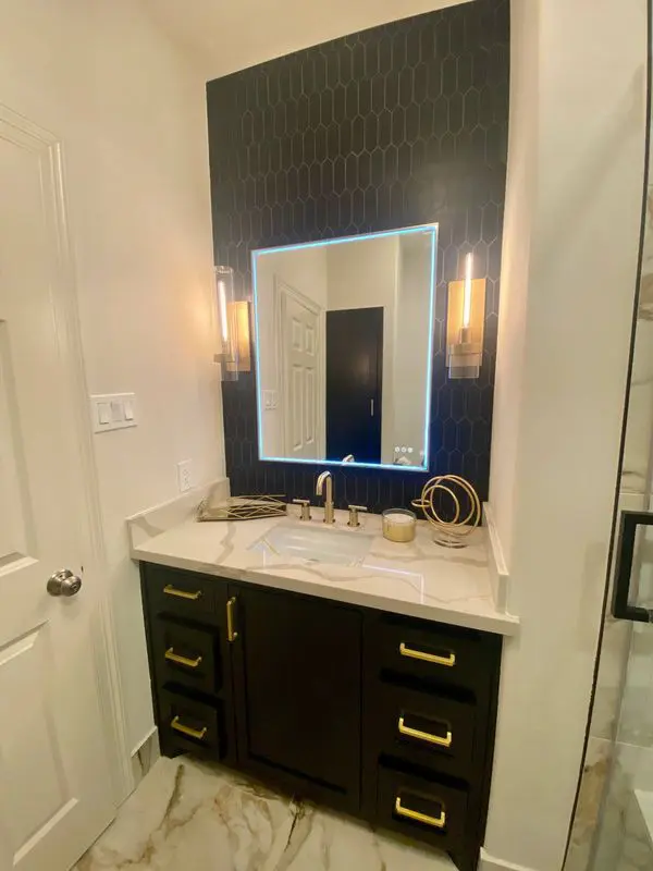 A black and gold bathroom with a mirror and sink.